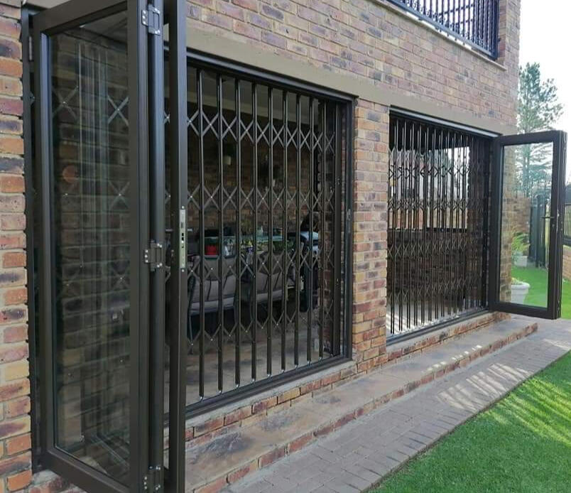 Brand new aluminium door and window frames shining in the bright sunlight against a clear blue sky and vibrant green grass. Professional installation for added durability and energy efficiency.